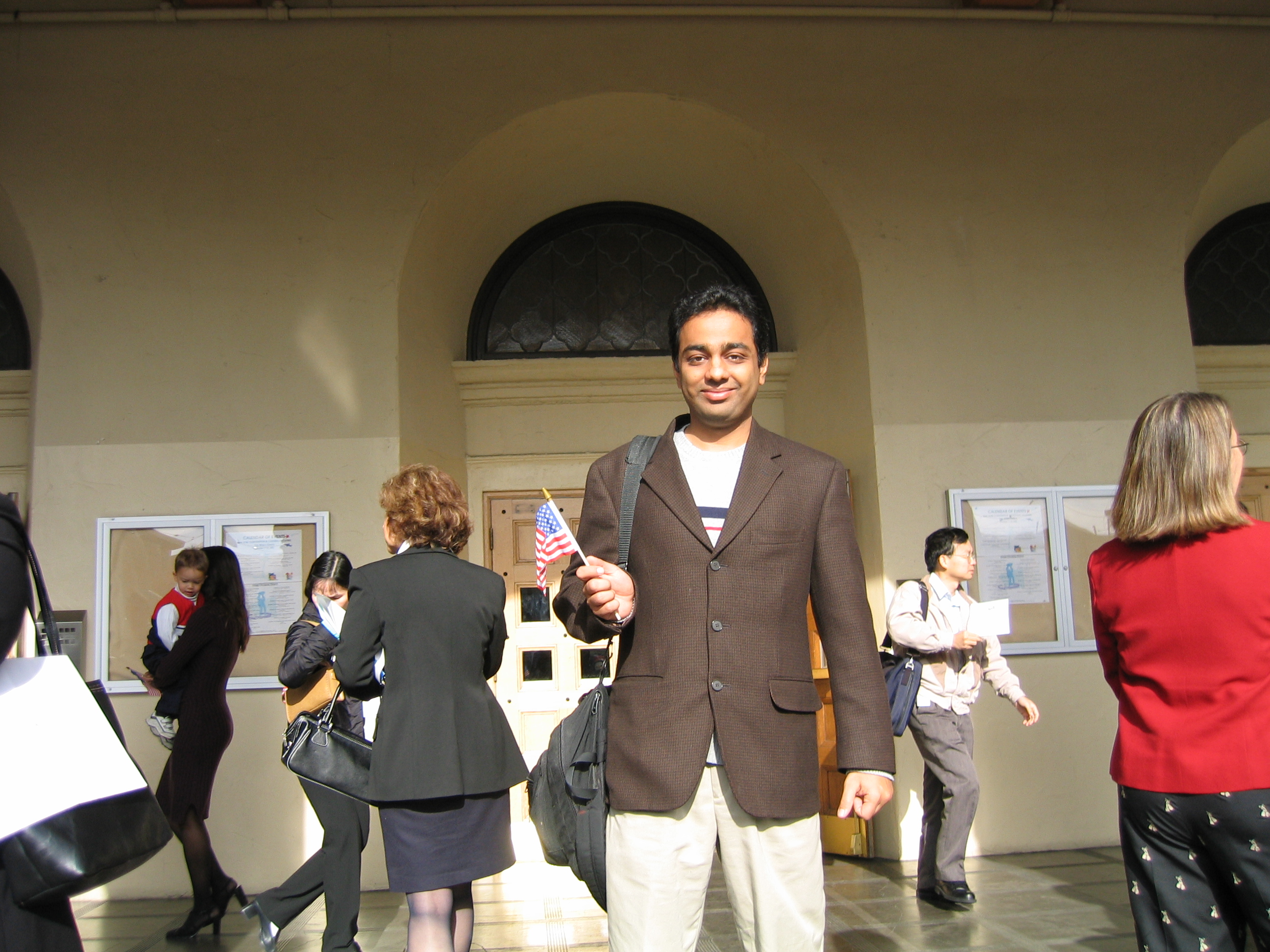 Rajiv holding an American flag inside the auditorium after the ceremony